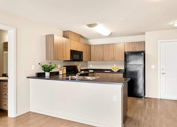 A kitchen with a black fridge and wooden cabinets.
