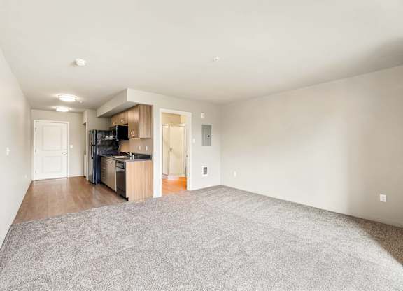 A spacious living room with a kitchenette in the background.