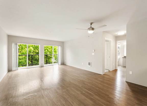 A room with a ceiling fan and sliding glass doors.