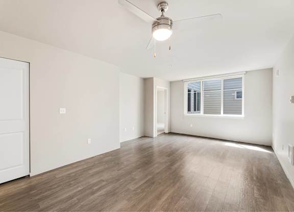 A room with a ceiling fan and wooden flooring.