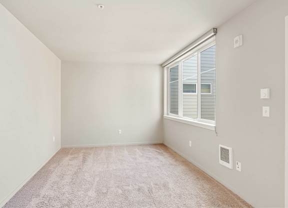 A room with a window and a carpet on the floor.