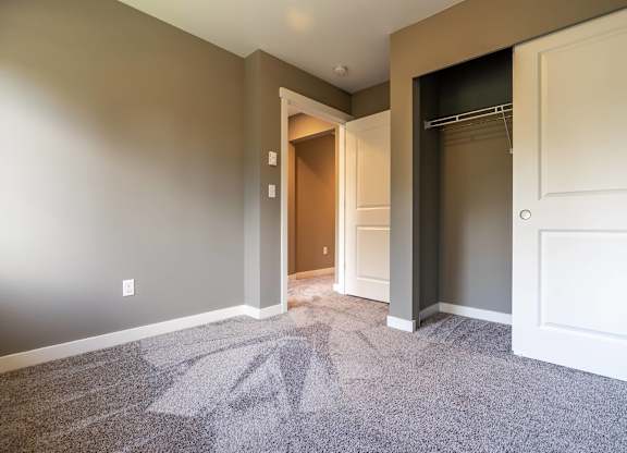 A room with a carpeted floor and a doorway leading to another room.