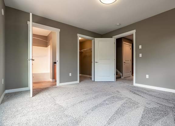 A room with a carpeted floor and three open doors.