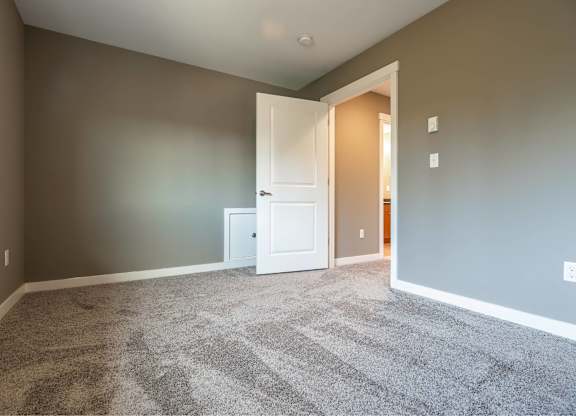 A room with a carpeted floor and a white door.