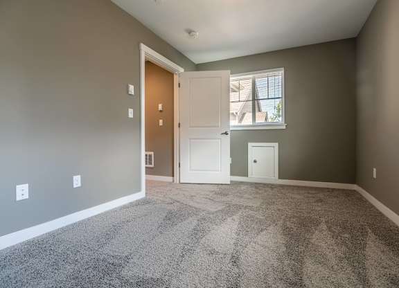 A room with a carpeted floor and a doorway leading to another room.