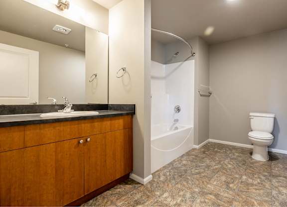 A bathroom with a toilet, sink, and mirror.