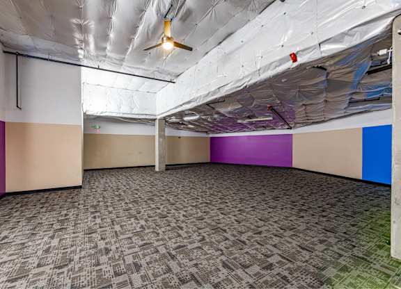 A room with a carpeted floor and a ceiling fan.