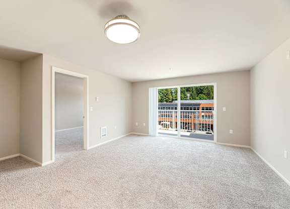 A spacious room with a carpeted floor and a window overlooking a construction site.