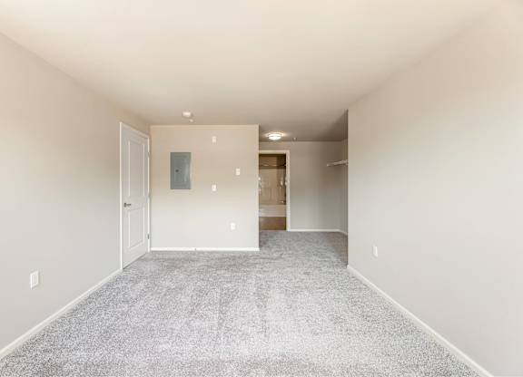 A spacious room with a carpeted floor and white walls.