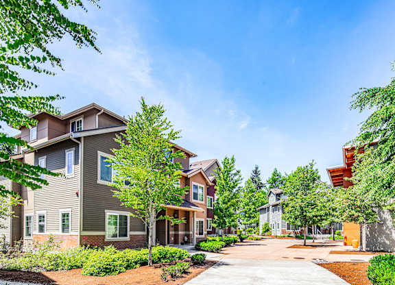 A row of houses with trees in front of them.