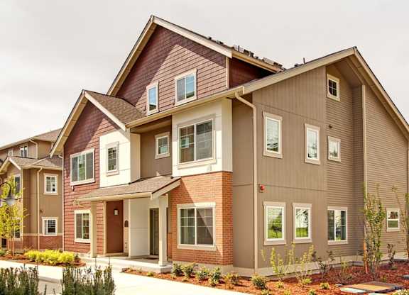 A modern two-story house with a red brick base and beige siding.