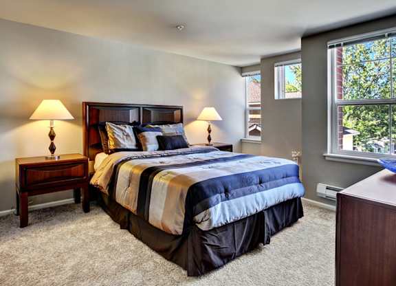 A bedroom with a large bed and two lamps.