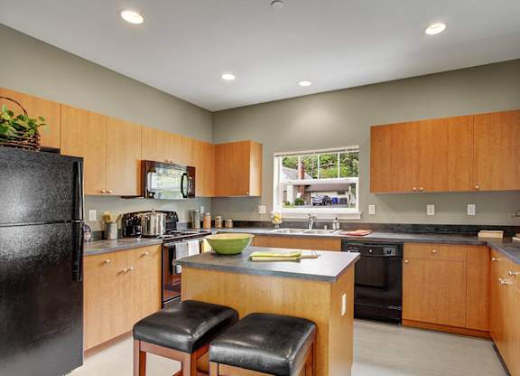 A kitchen with wooden cabinets and black appliances.