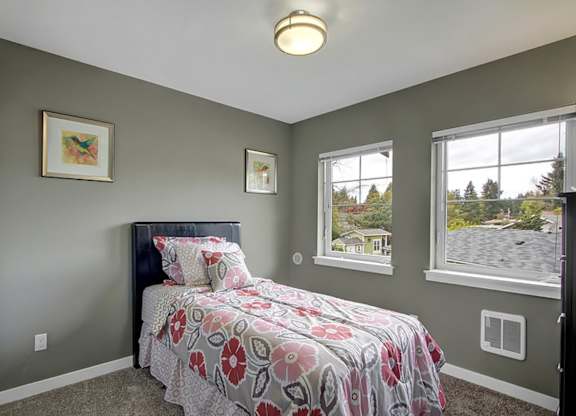 A bedroom with a bed, two windows, and two pictures on the wall.