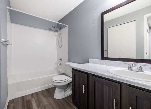 A white toilet sits in a bathroom with a white tub and a white sink.