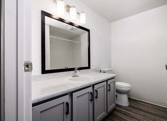 A bathroom with a toilet, sink, and mirror.