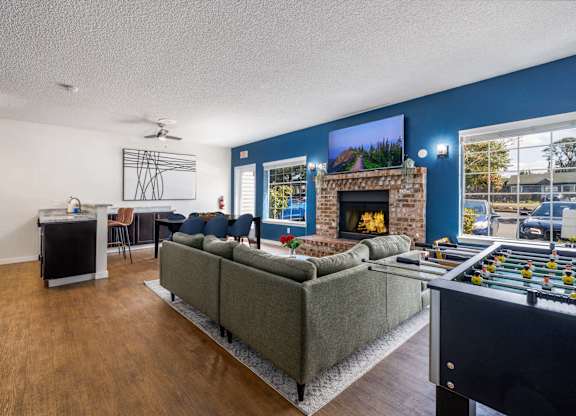 A living room with a grey couch, a fireplace, and a foosball table.