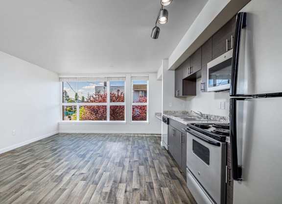 A kitchen with a stove top oven and a window with a view of a tree with red leaves.