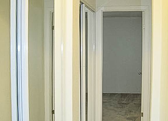 A hallway with a white door and a white wall.