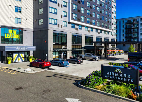 A red car is parked in front of a building with a sign that says