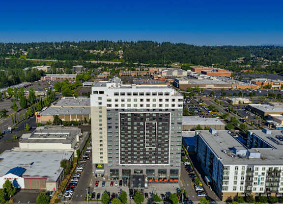 A large building with a lot of windows is in the middle of a parking lot.