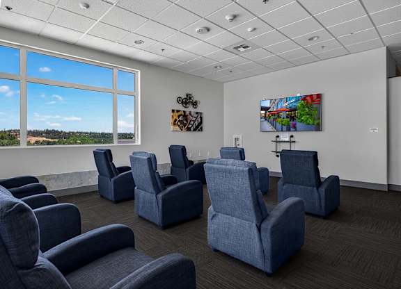 A room with blue chairs and a painting on the wall.