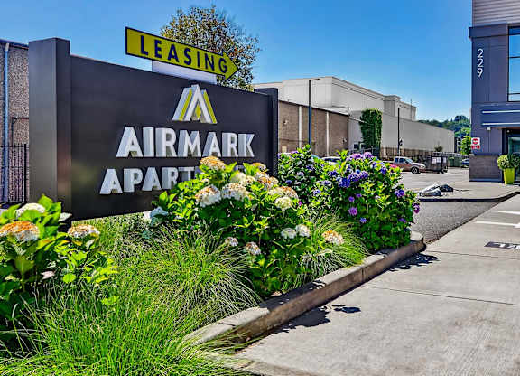 A sign for Airmark Apartments is displayed in front of a building with a leasing sign above it.