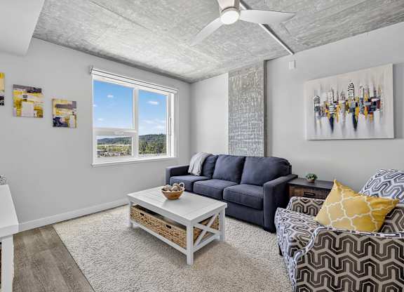 A living room with a grey sofa, a white coffee table, and a painting on the wall.
