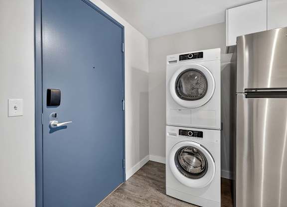 A blue door is on the left and a washing machine is in the middle of the room.