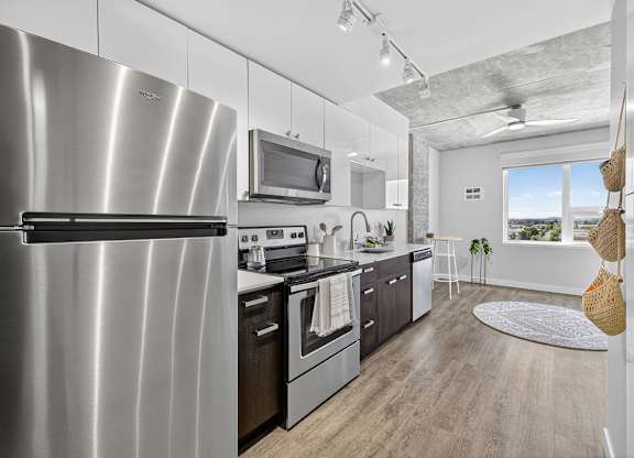 A modern kitchen with a stainless steel refrigerator and wooden flooring.