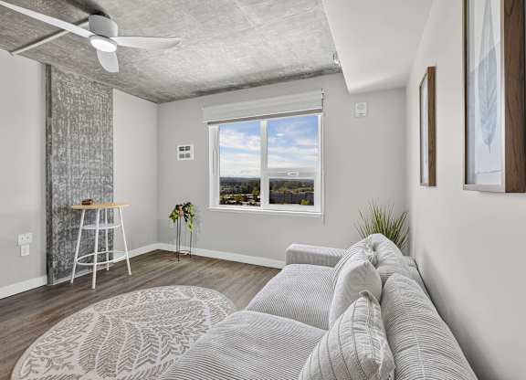 A living room with a grey couch and a ceiling fan.