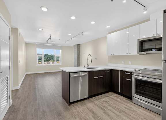 A modern kitchen with stainless steel appliances and wooden floors.
