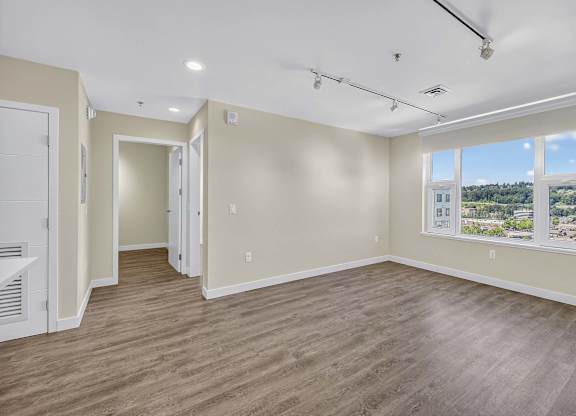 A spacious room with wooden flooring and a large window.