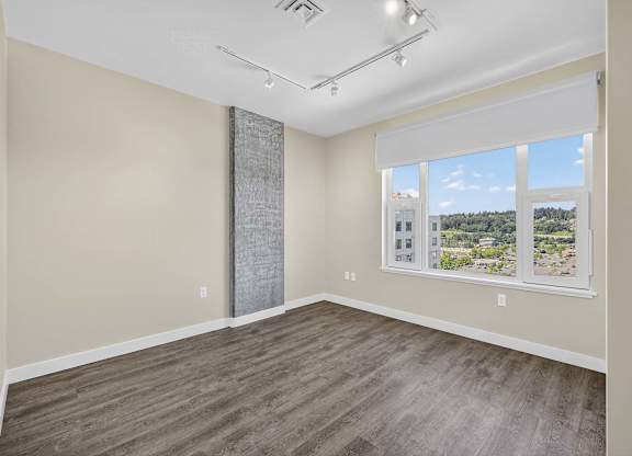 A room with a large window and a wooden floor.