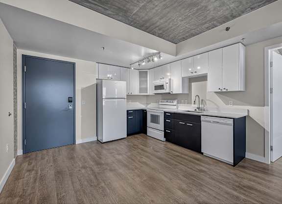 A kitchen with white cabinets and a black fridge.