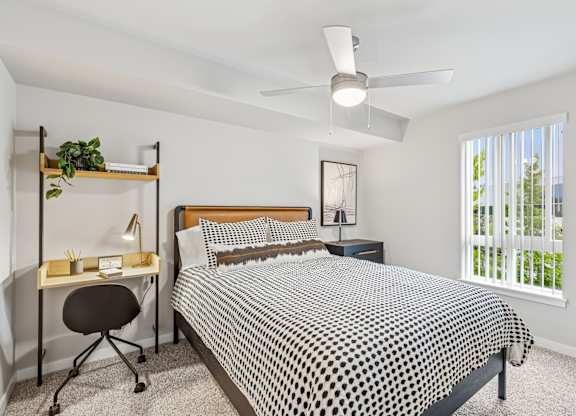 A bedroom with a bed, desk, and chair.