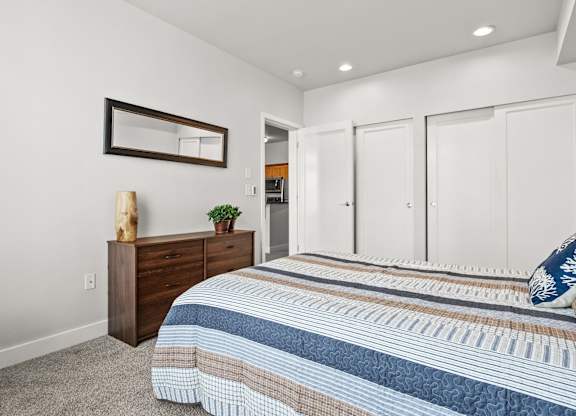 A bedroom with a bed, dresser, and mirror.