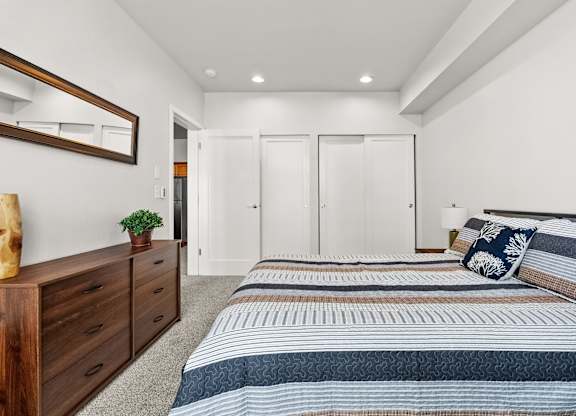 A bedroom with a bed, dresser, and mirror.
