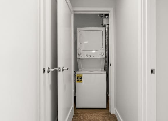 A white dryer is in a small white room.