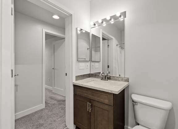 A bathroom with a white toilet, sink, and mirror.