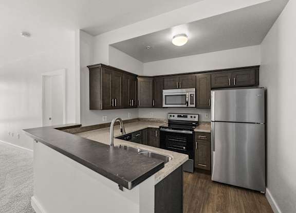 A modern kitchen with a stainless steel refrigerator and dark brown cabinets.