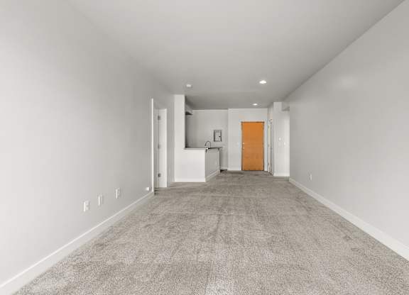 A long, empty hallway with a carpeted floor and white walls.