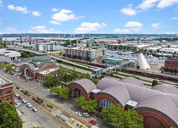 A city street with a large building with a curved roof in the foreground.