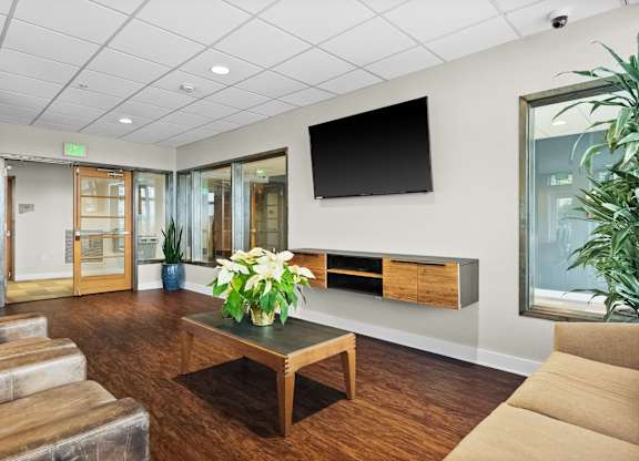 A living room with a wooden floor and a flat screen TV mounted on the wall.