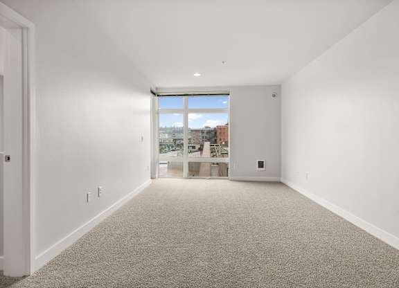 A large empty room with a window overlooking a cityscape.
