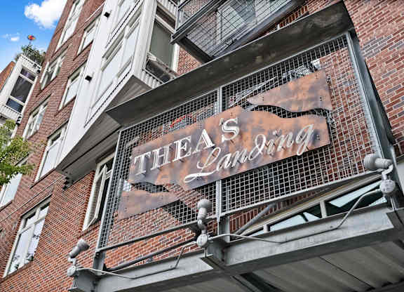 A sign for Thea's Lounge is displayed on a building.