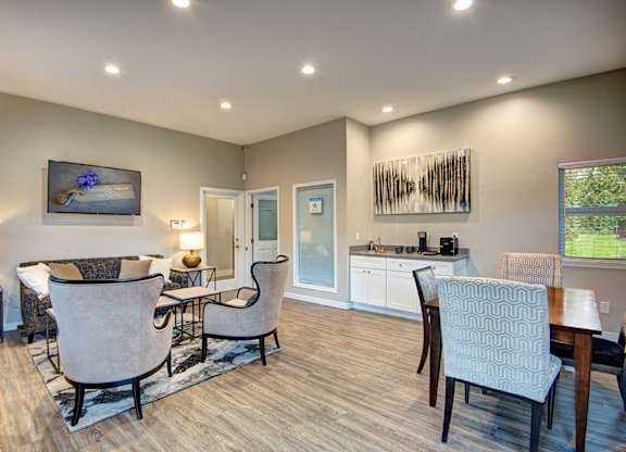 A well-lit living room with a dining area and a kitchen in the background.