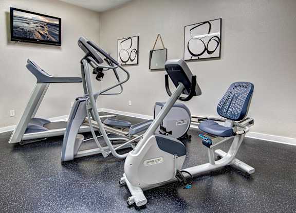 A gym room with a rowing machine and a stationary bike.