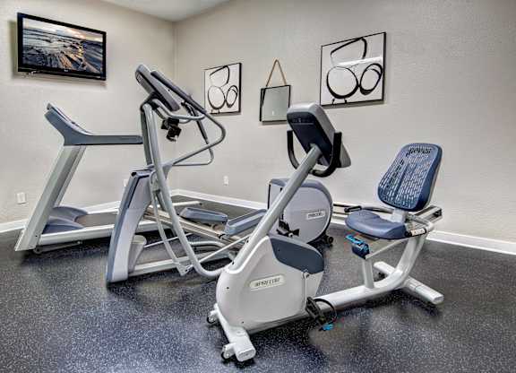 A gym room with a rowing machine and a stationary bike.
