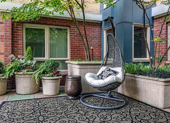 A chair sits on a patio with a brick wall behind it.